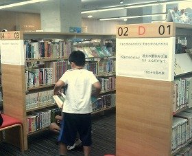 本を書架に並べる一日図書館員の子供たち。