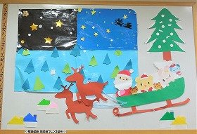 写真　冬の星空。空飛ぶソリは、２頭のトナカイが引いている。ソリには、サンタクロースとどうぶたちがのっている。12月の壁面飾りです。