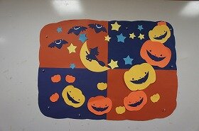 画像:夜空を背景に、魔女やかぼちゃたちが楽しそうにハロウィンパーティーをしている壁面装飾です。