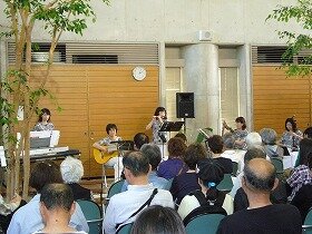 画像:江坂ロビーフェスタで演奏する、あんさんぶるばっかなからるさんの様子。