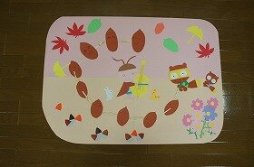 画像:どんぐりたちが、バイオリンを奏でるコオロギを囲んで大合唱している壁面装飾です。