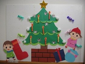 画像:モミの木が飾られ、その下にクリスマスプレゼントとくつしたが置かれ、子どもがサンタさんを待っている。