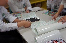 画像:本に貼りつけるコーティングシールを切っている写真。