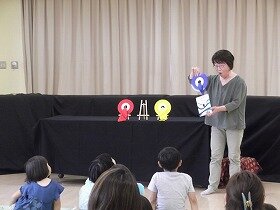 画像:レコードを使ったマジックをしている女性と、聞いている親子