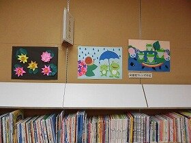 画像:4匹のカエルが池に浮かぶ葉っぱの上にいますよ。2匹のカエルは傘をさしてお出かけかな。ピンクのあじさい