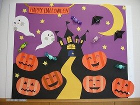 画像:夜のお城の周りにおばけとコウモリが飛び、顔の形にくりぬいたかぼちゃが道の両側に並んでいる光景を描い