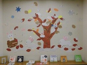 画像:大きな木やその周りに雪が積もり、うさぎたちがとび跳ねている壁面飾り。