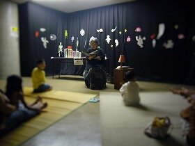 画像:明かりが消えてきた部屋で、お話に耳を傾ける様子。