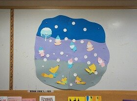 画像：雪が降り積もる場所で、きつねと一緒に遊ぶ子どもたちの壁面装飾です。