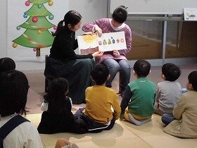 画像：絵本を読む学生ボランティア達と見る子供達
