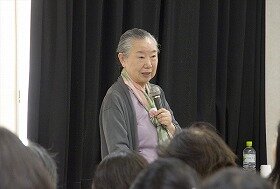 画像：マイクを片手に講演中の正置友子さん