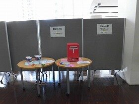 画像：エコおもちゃの展示風景。飲料パックで作った電車2台と赤い郵便ポスト。