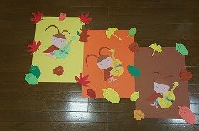 画像：イチョウのはっぱやどんぐりに囲まれて、コオロギ3匹がバイオリンを奏でている壁面装飾です。