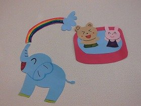 画像：プールあそびするクマとうさぎに鼻で水をかける象。