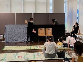 画像：マジックをしている演者と見ている親子。