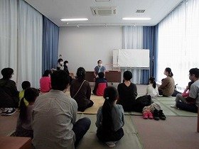 画像：おはなし「ライオンにばけたろば」に耳を澄ます参加者たち。