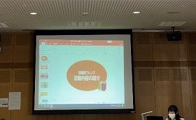 画像：スクリーンに映した画像に沿って職員が図書館フレンズについて説明している様子。