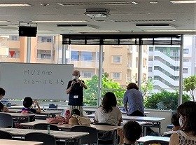 画像：作り方を説明する講師と熱心に説明を聞く親子