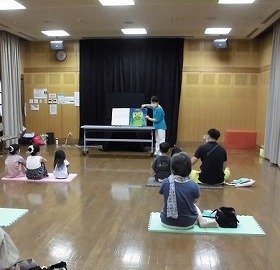 画像：吹田おはなしの会さんが演じる大型絵本に、お客さんが見入っているようす。