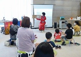 画像：山田駅前図書館の職員が子供たちに向けて絵本『トヤのひっこし』を読んでいる様子。