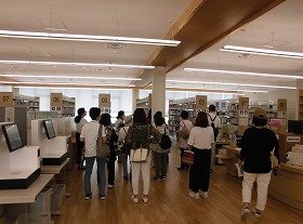 画像：大人向けの本のコーナーを案内している様子。