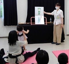 画像：大型絵本ぴょーんを読む職員と聞いている親子。