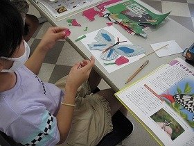 画像：新聞ちぎり絵で蝶々を作成している様子。
