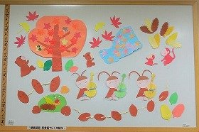 画像:紅葉している木の下で、たき火をかこむどんぐりたち。