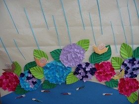 画像:雨が降るなか池ではメダカが泳いでおり、アジサイが咲いている間にカタツムリがいる。