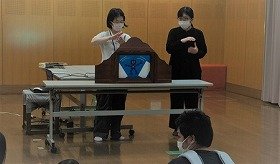 画像:手話をしながら紙芝居をしている写真。