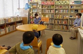 画像:読み聞かせをする実習生とじっと聞いている子ども達。