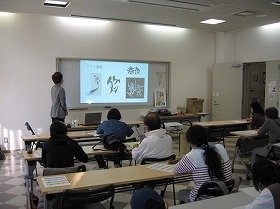 画像:スクリーンに作品を映し出し作字のコツを説明している様子。