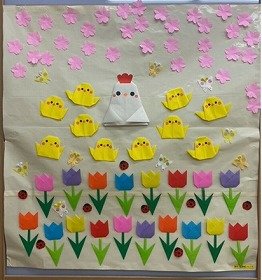 画像:桜とチューリップが咲き乱れる中、にわとりとひよこが集まっている。