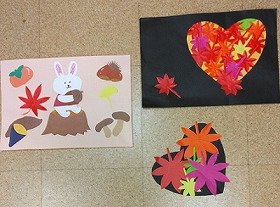 画像:ドングリを持ったウサギの回りに 柿、栗、キノコ、サツマイモ、もみじとイチョウの葉が描かれた飾りと、ハートの形にくり抜いた画用紙に黄色や赤に色付いたもみじの葉を貼って、秋の様子を表現した飾り。