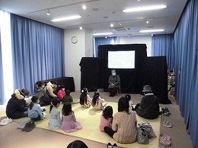 画像:女性が語るおはなしを聞く親子。