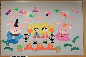 画像:花とおひなさまがいっぱいならんでいる、ひな祭りの壁面飾り。