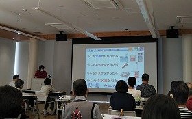 画像:多目的室内で講師がスライドを用いて講義中