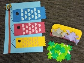 画像：切り紙の鯉のぼりと兜飾り。緑鮮やかな切り紙のクローバーが添えられています。