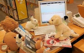 画像：ぬいぐるみたちが、図書館のカウンターで本の貸出をしています。
