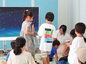 画像：星空におりがみを貼る子供たちの様子。