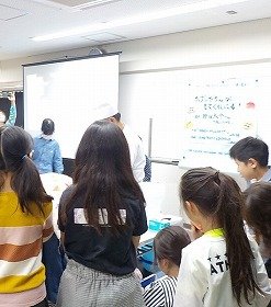 写真3： 講師が魚をさばく様子を見つめる子供たち。