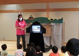 画像：紙芝居「春だよニャーオン」を聞く子供たち。
