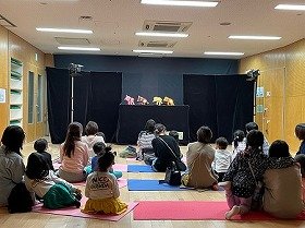 画像：横に首をかしげているぶたさん、たぬきさん、きつねさん、ねこさんの人形と、それを見ている観客。