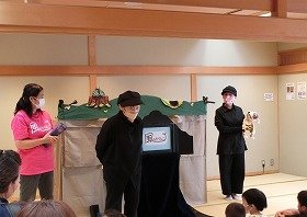 画像：風のぶらんこの皆さんと犬のぬいぐるみ「ブッチー君」が、参加者の皆さんにご挨拶。