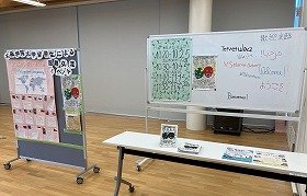 写真2：入口に設置されたボード。留学生の自己紹介やイベントプログラム、多言語でようこそというあいさつが書かれている。