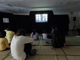 写真：参加者が、影絵芝居「ブレーメンの音楽隊」を見ている様子。
