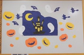 写真：三日月の夜。おばけ屋敷。それをとりまく魔女、コウモリ、ハロウィンのカボチャ。10月の壁面装飾です。