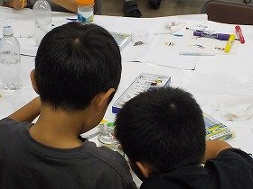 写真1：参加者の兄弟が相談しながら瓶を塗る様子