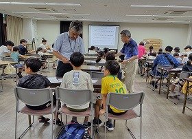 画像3：参加者に工作の手順を説明する講師