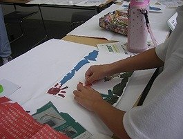 写真1：ちぎった新聞を画用紙へ貼っているところ